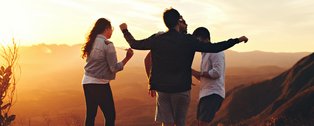 Vier Jugendliche im Sonnenuntergang auf einem Hügel