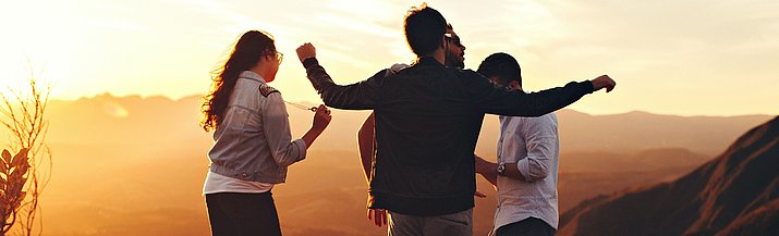 Vier Jugendliche im Sonnenuntergang auf einem Hügel