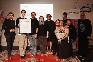 Mehrere junge Menschen posieren mit einer Urkunde für die Kamera