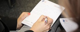 Hand, die etwas auf einen Block schreibt