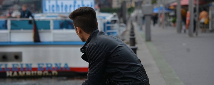 Ein junger Mann sitzt am Hafen