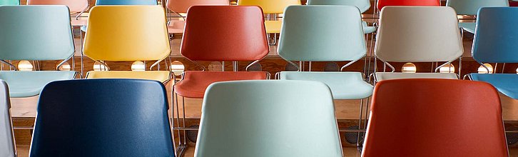 Mehrere bunte Stühle, die in Reihen hintereinander stehen