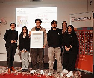 Mehrere junge Menschen posieren mit einer Urkunde für die Kamera