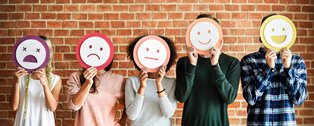 Ein Reihe Menschen, die sich Smiley-Schilder vor das Gesicht halten