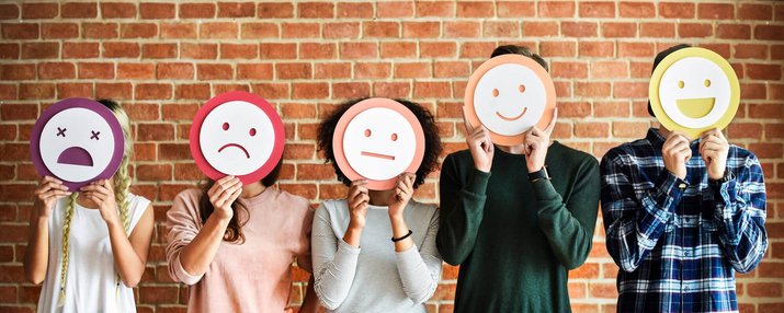 Ein Reihe Menschen, die sich Smiley-Schilder vor das Gesicht halten