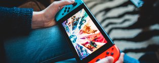 Person mit Gaming-Konsole auf dem Schoß