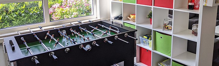 Blick in einen Jugendraum (ohne Personen): Kicker und Regal mit Sachen für die Jugendarbeit