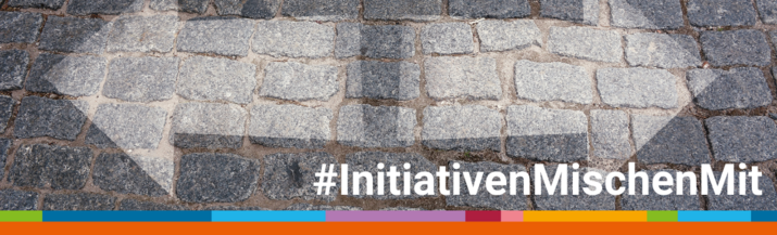Zwei Pfeile in unterschiedliche Richtungen, die auf Pflaster gemalt sind. Text #InitiativenMischenMit